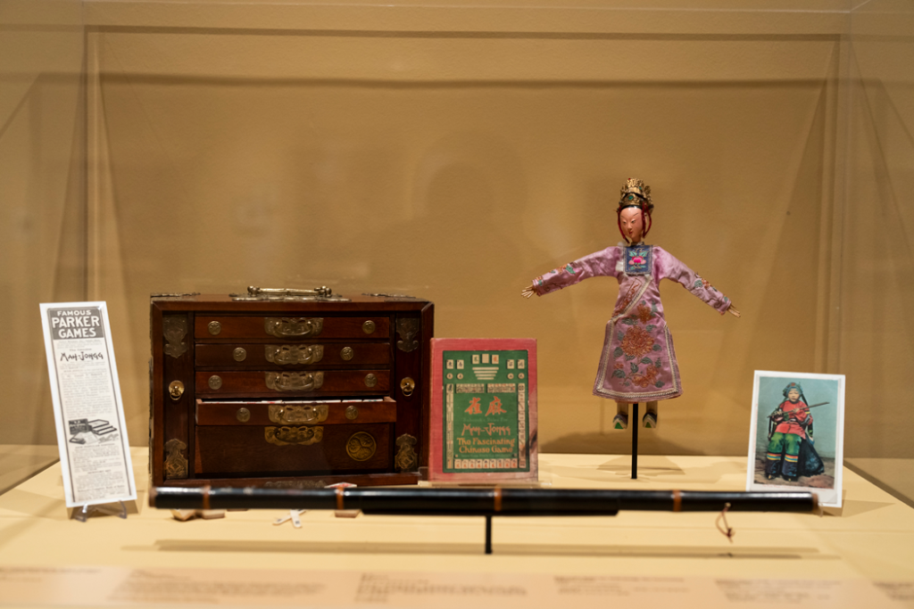 A glass case containing a jewelry box, a doll and postcards