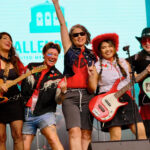 Women band performing energetically on stage.
