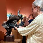 Person examining a sculpture in a gallery.