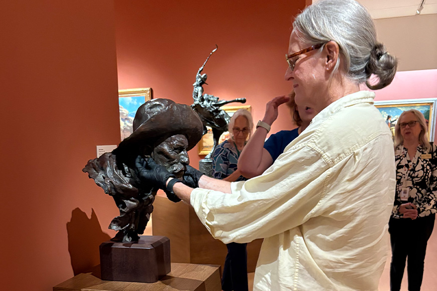 Person examining a sculpture in a gallery.