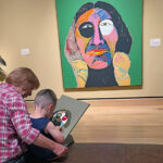 Child and adult viewing colorful abstract painting.