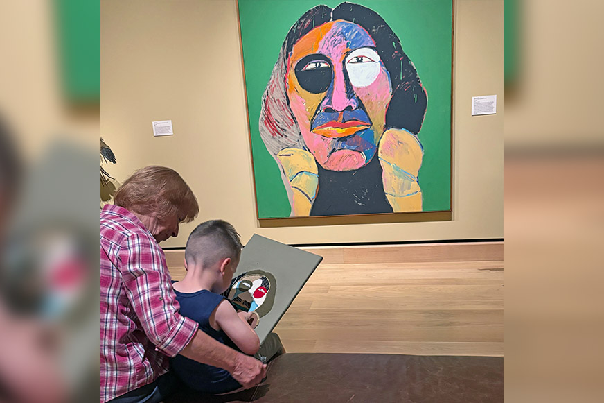 Child and adult viewing colorful abstract painting.
