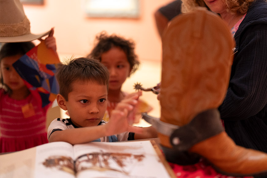 Children examining cowboy boot and book.
