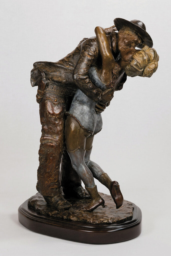 A bronze sculpture from Frontier Gallery depicts a cowboy dipping and kissing a woman, both dressed in Western attire, set on an oval base.
