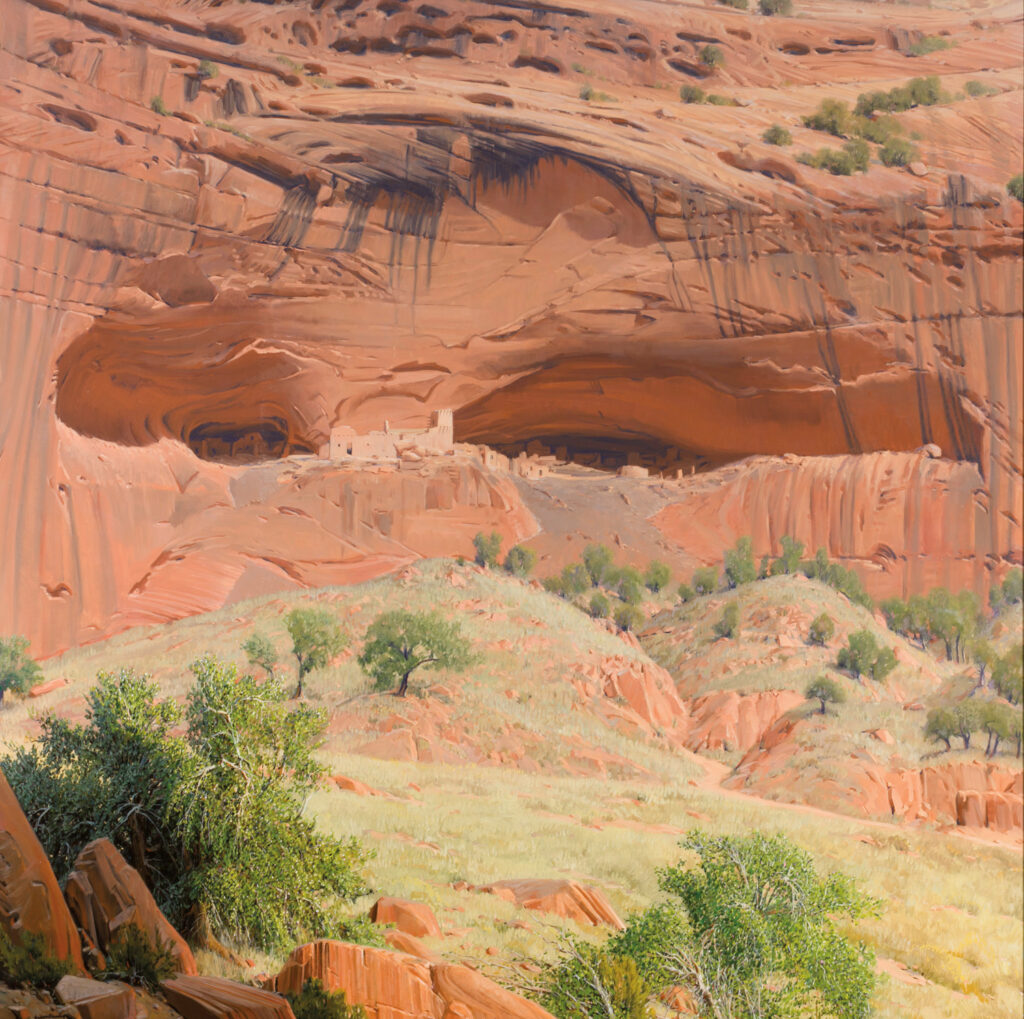 Ancient cliff dwellings built into a large red sandstone alcove, surrounded by rocky terrain and sparse vegetation, welcome visitors like an Introductory Gallery to the region’s rich history.