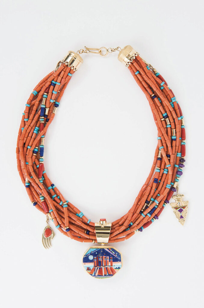 Multi-strand Jewel Box necklace with orange, turquoise, and purple beads, gold accents, and three pendants—a painted disk, a hand, and an arrowhead.