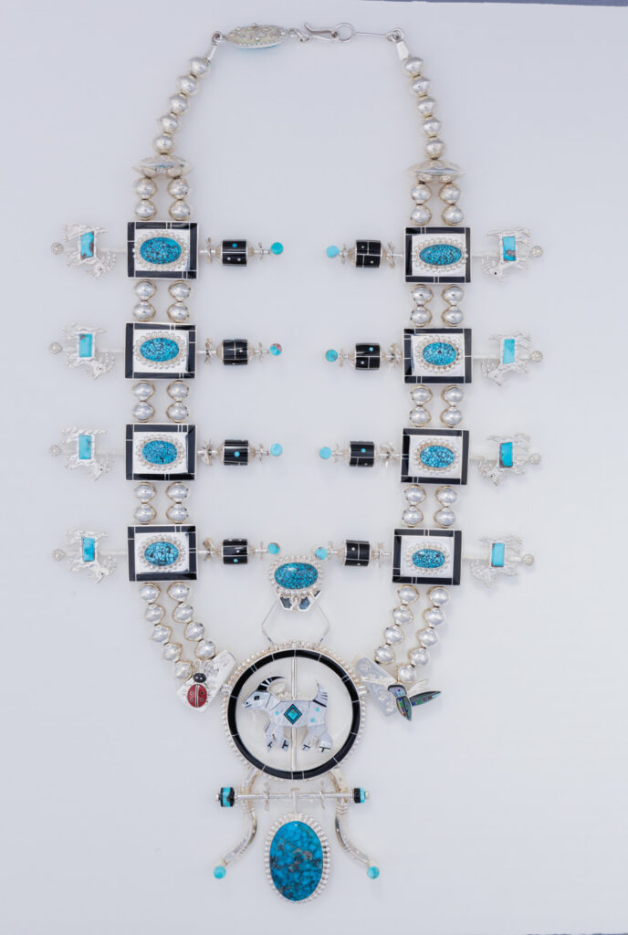 A Jewel Box treasure: this silver necklace features turquoise stones, black accents, geometric designs, a large round pendant, and multiple beaded strands.