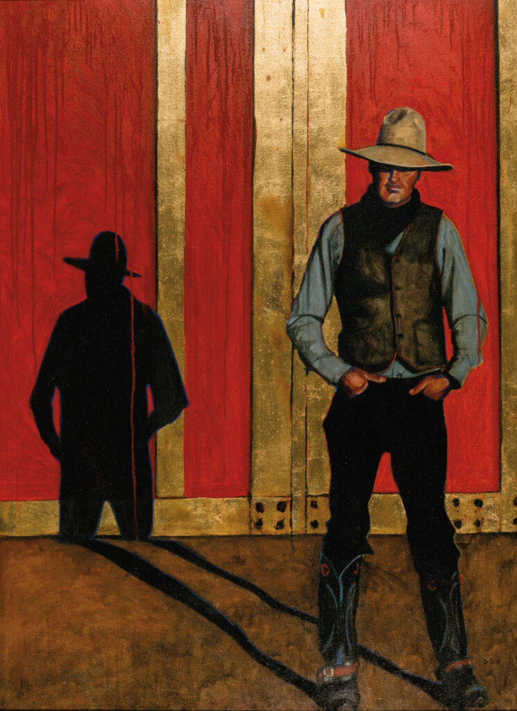 A man in a cowboy hat and vest stands against a red and gold wall at the New West Gallery, casting a dark shadow beside him on the ground and wall.