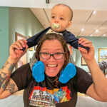 Smiling woman with baby on her shoulders.
