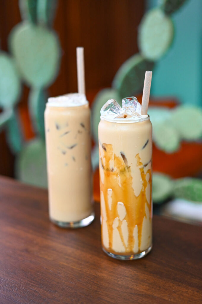 Two iced coffees on a table, one with a caramel drip.