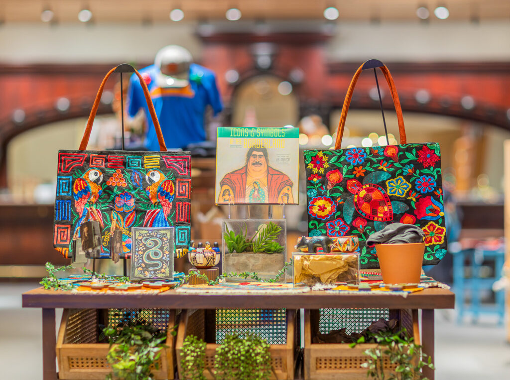 A display of merchandise themed to a past exhibition "Icons & Symbols of the Borderlands" including an embroidered tote bag and a book for the exhibition.